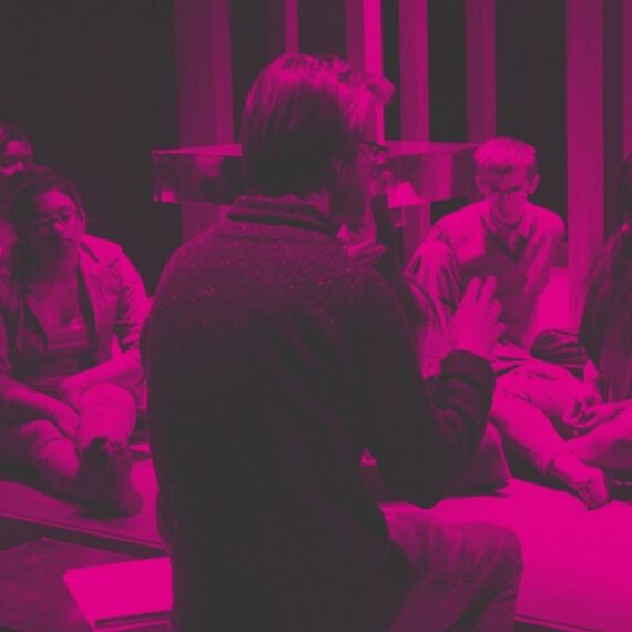 Image of young people sitting on a stage listening