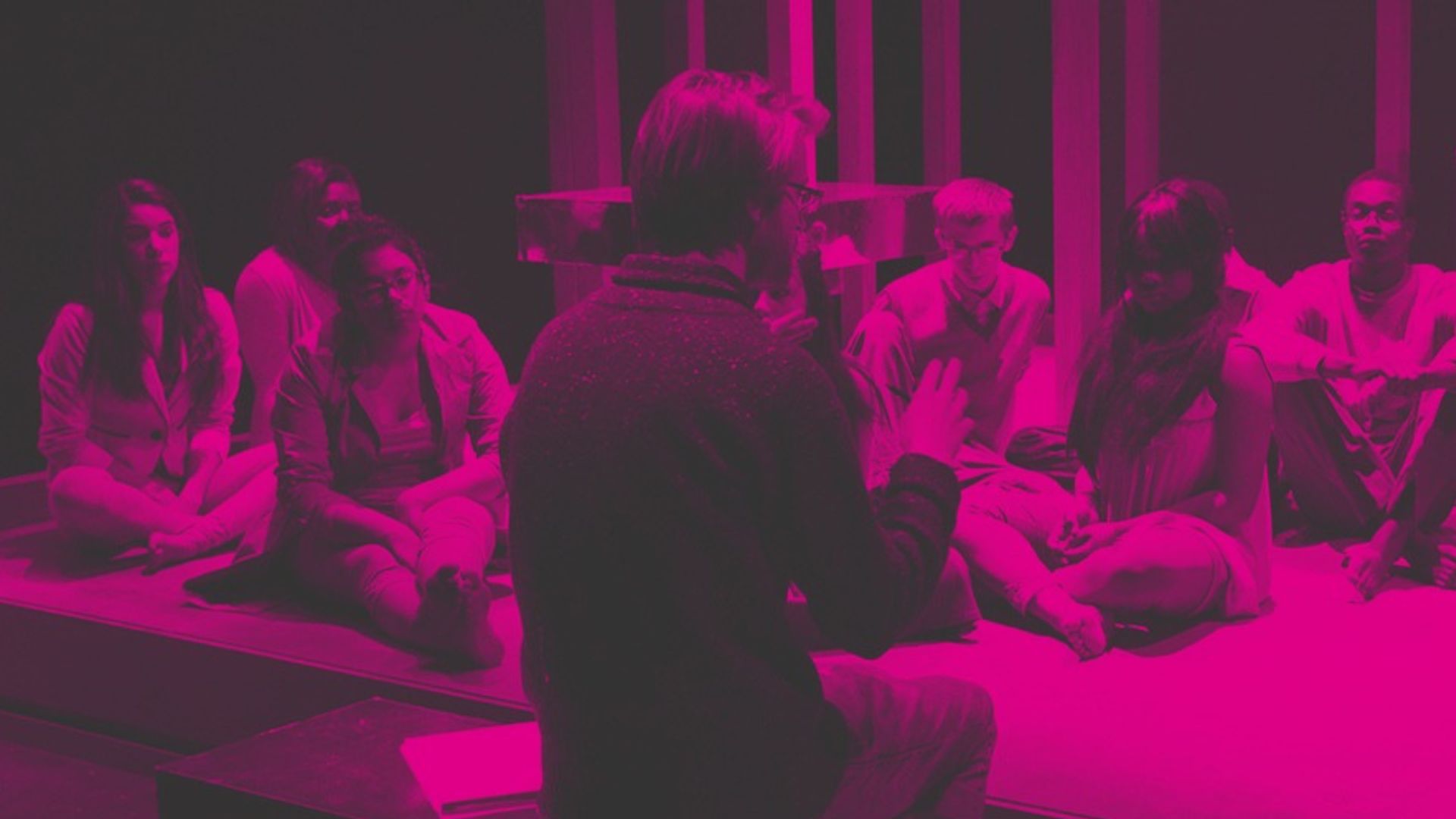 Image of young people sitting on a stage listening