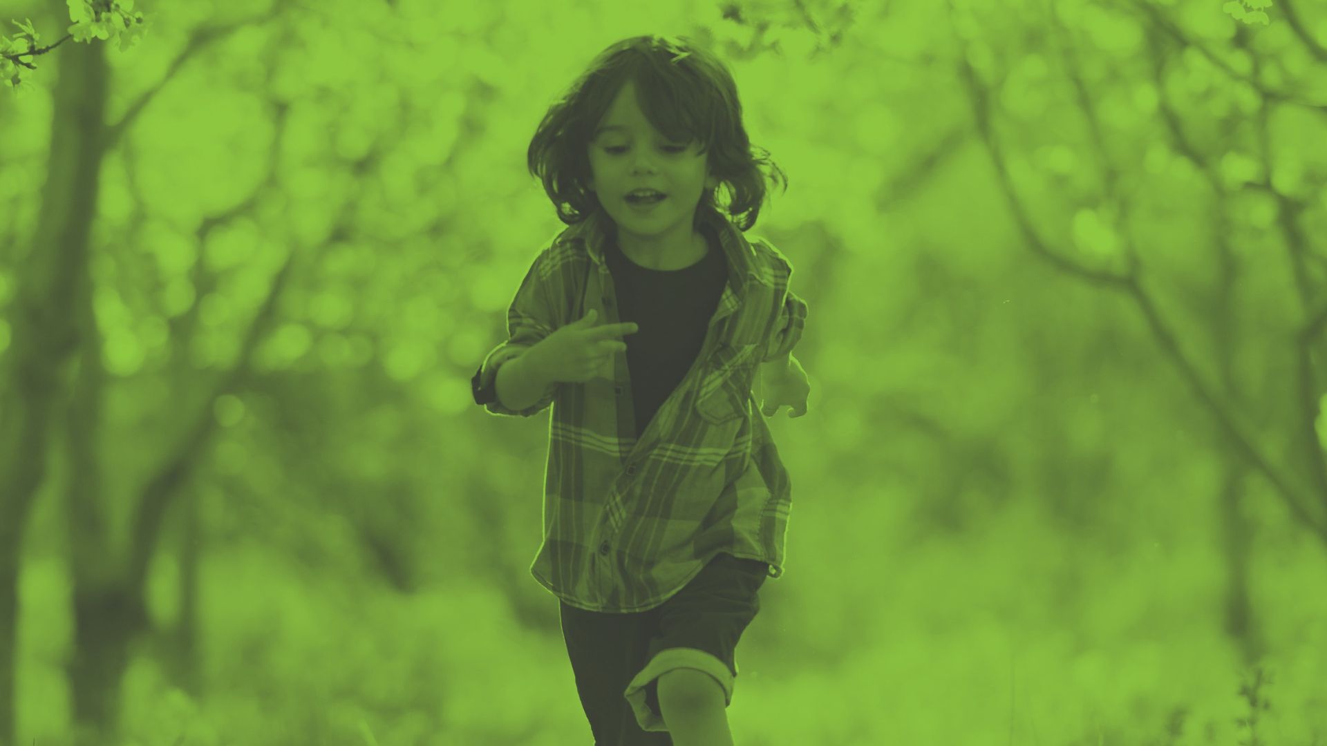 Photo of a child running through a green and wooded space