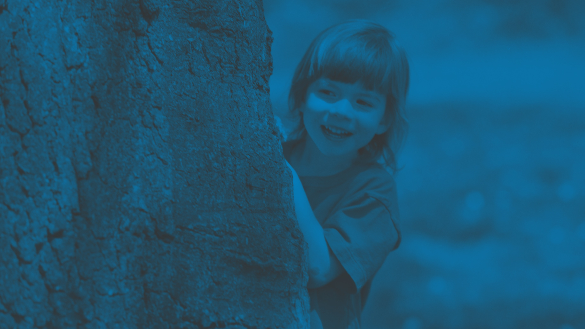 Image of a child playing near a tree in an outside setting - Schools within the UK can apply for grants for community-led tree-planting projects